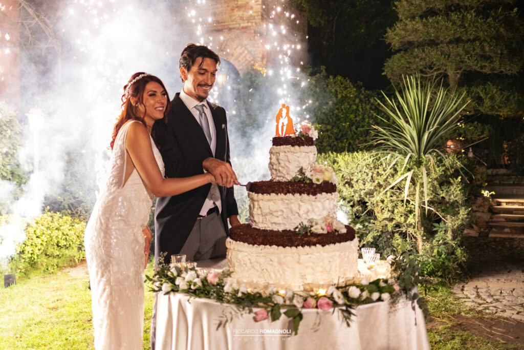 Foto del Taglio della Torta con fontane luminose alle spalle degli sposi